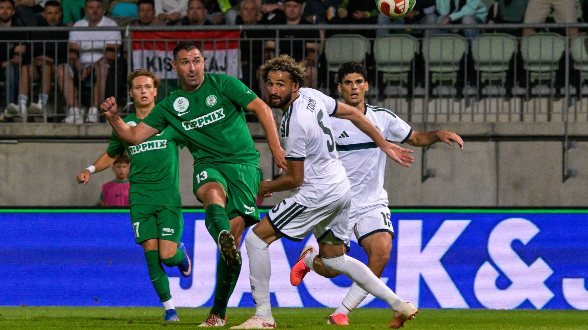 Böde Dániel, a Paks játékosa (b2) gólt lő, mellette Ahmed Tuba, a Panathinaikosz játékosa melett a labdarúgó Konferencia-liga selejtezőjének 2. fordulójában játszott Paksi FC – Panathinaikosz mérkőzésen a Paksi FC Stadionban 2026. július 23-án.