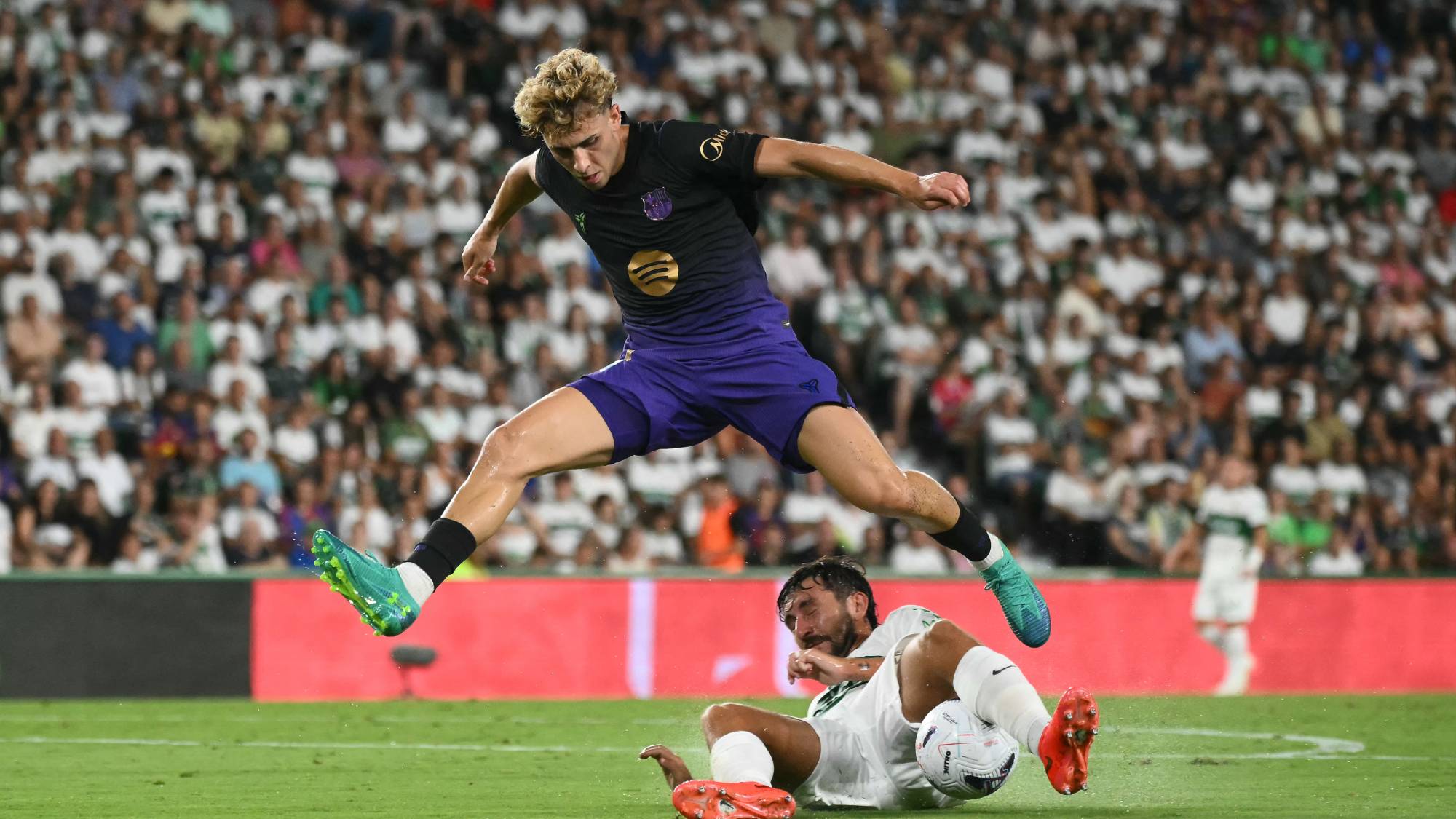 Barcelona's Spanish midfielder #07 Fermin Lopez (up) fights for the ball with Elche's Spanish defender #23 Victor Chust during the Spanish league football match between Elche CF and FC Barcelona at Martinez Valero Stadium in Elche on August 23, 2026.